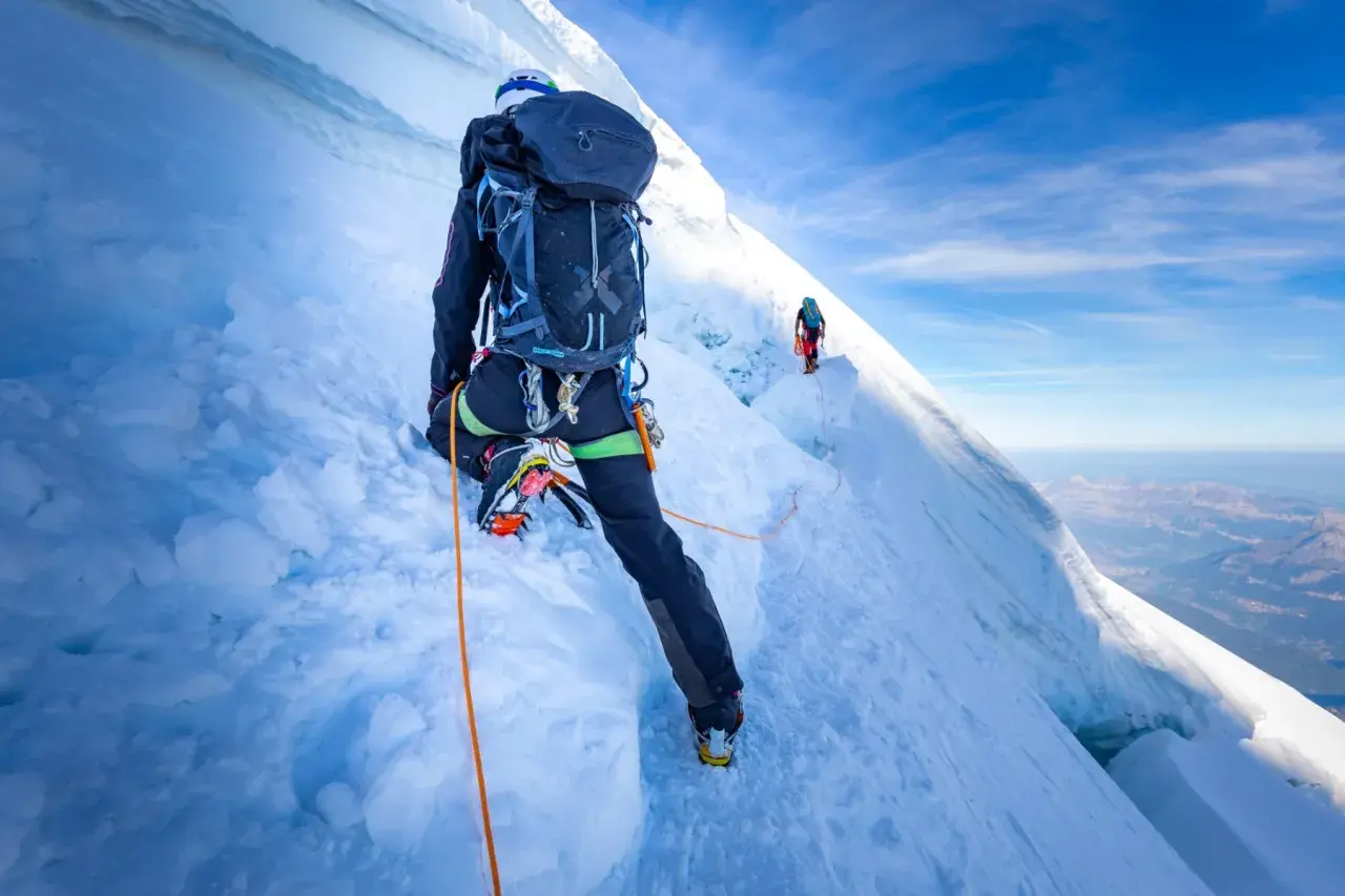 Bergsteiger auf dem Mont Blanc Normalweg, gesichert durch ein Seil, steigen über eisige Hänge.