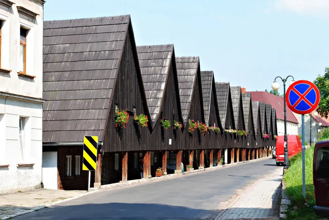 Rząd drewnianych domów z charakterystycznymi spiczastymi dachami i kwitnącymi balkonami. Chełmsko Śląskie atrakcje zachwycają unikalną architekturą.