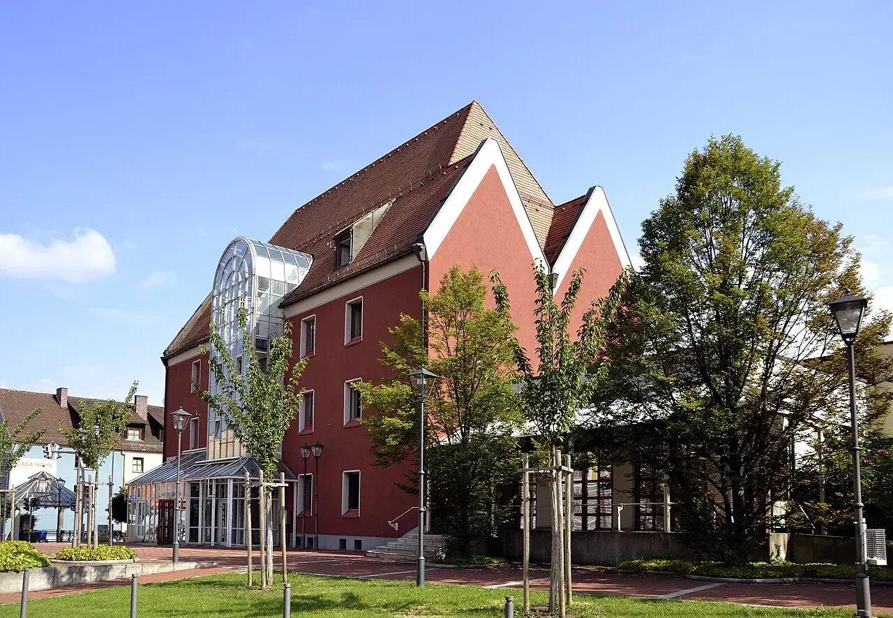 Das Handwerksmuseum Deggendorf präsentiert sich in einem modernen Gebäude mit auffälliger Glasfront und roten Fassaden.