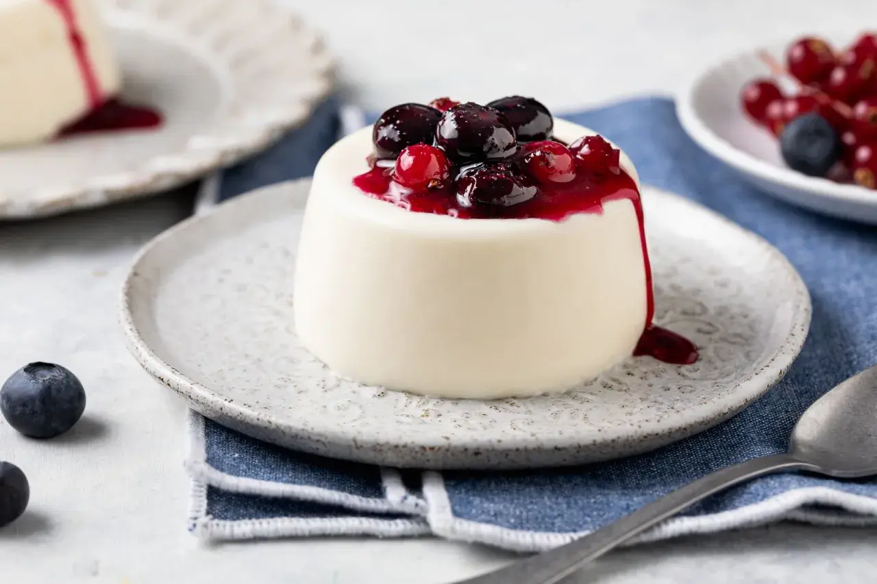 Panna cotta bianca con topping di frutti di bosco e salsa rossa. Ingredienti panna cotta freschi e invitanti.