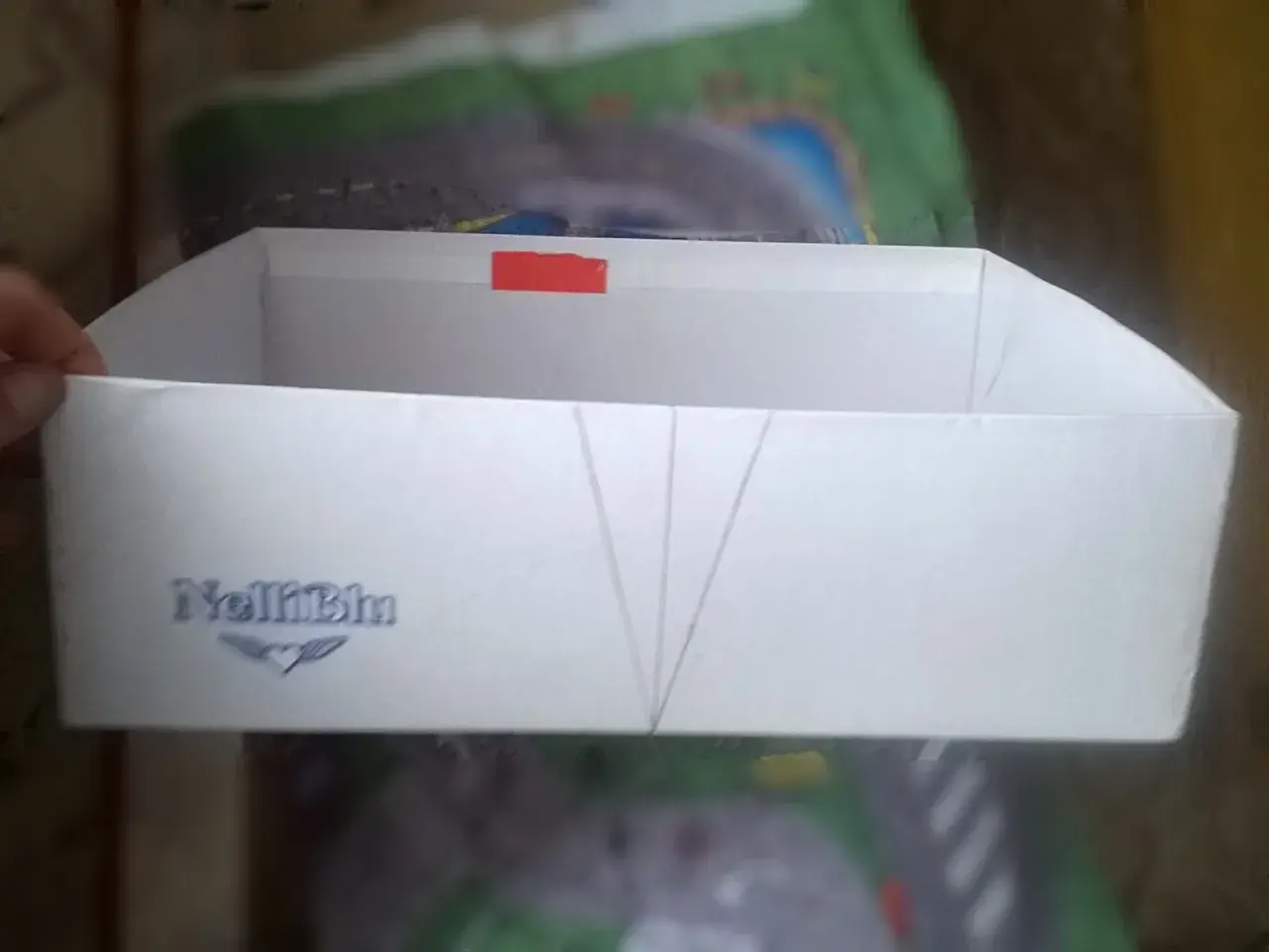 Białe pudełko z logo "NelliBlu" i zaznaczonymi liniami, gotowe do stworzenia własnego **organizer diy**.