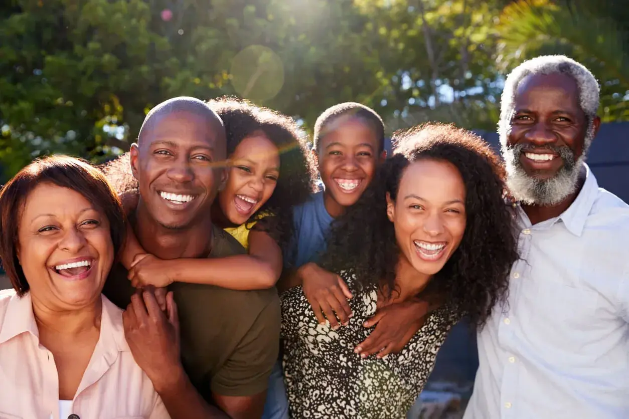 Una familia multigeneracional sonríe y ríe junta al aire libre, disfrutando de actividades de día familiar.