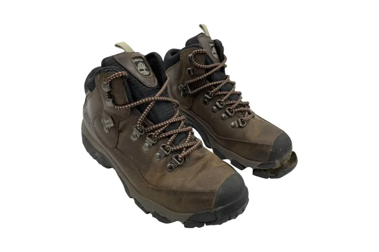 Well-worn brown hiking boots, one with the sole coming off, showing signs of many adventures.