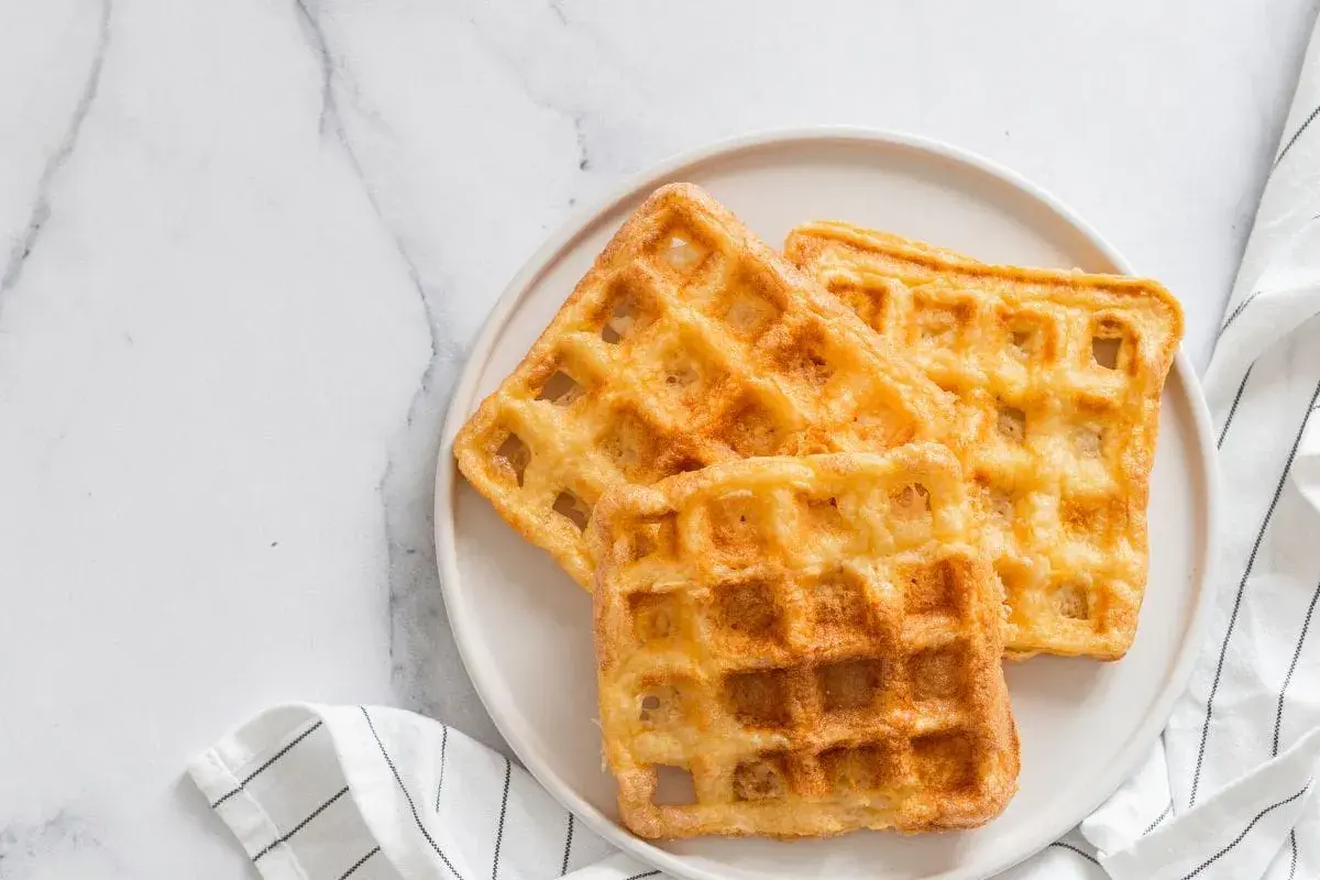 Trois gaufres au sarrasin dorées et croustillantes sur une assiette blanche, prêtes à être dégustées.