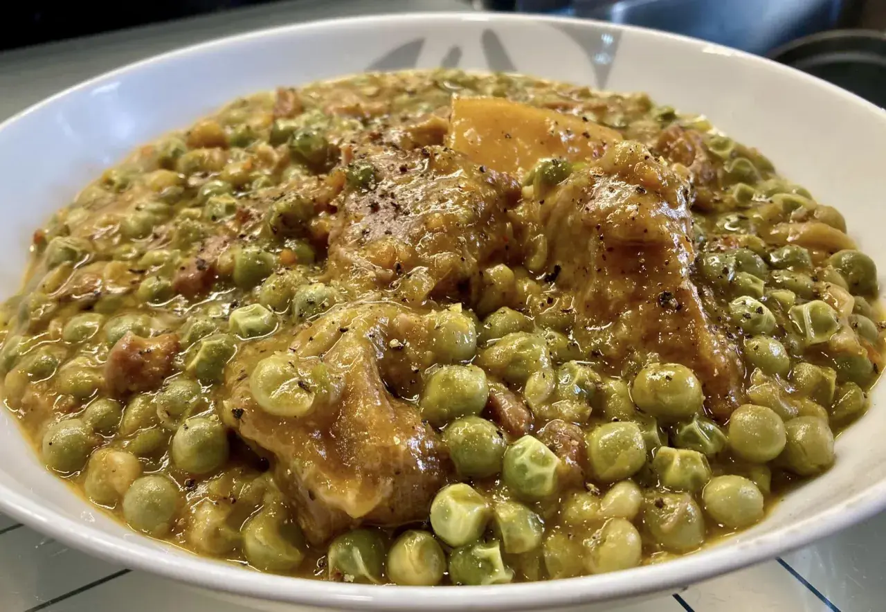 Un saporito spezzatino con piselli, teneri pezzi di carne e verdure in un sugo denso e profumato, pronto per essere gustato.