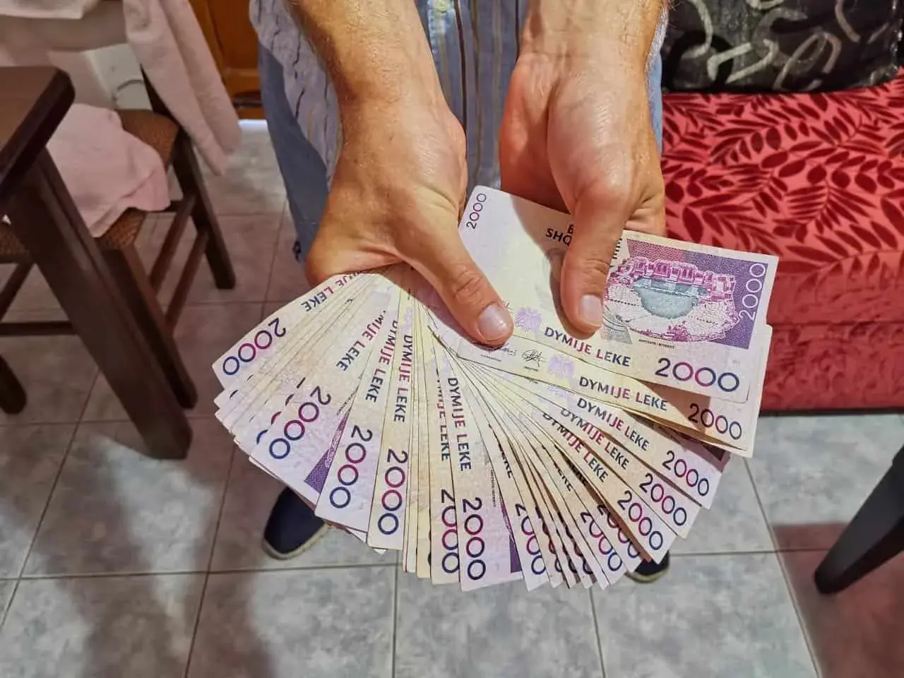 Hände halten einen Fächer aus albanischem Geld, 2000 Lek-Scheine.