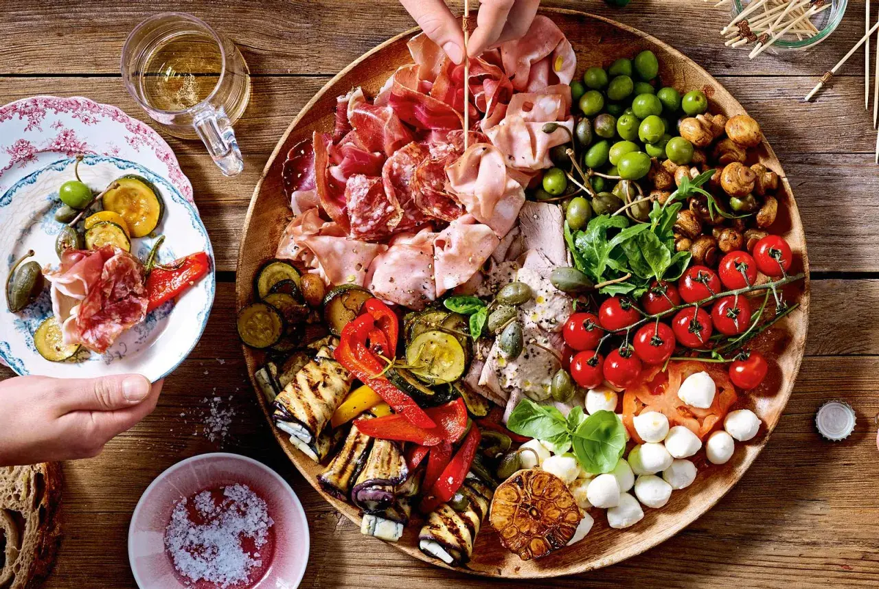 Eine üppige antipasti platte mit Wurst, Käse, Oliven, gegrilltem Gemüse und Tomaten.
