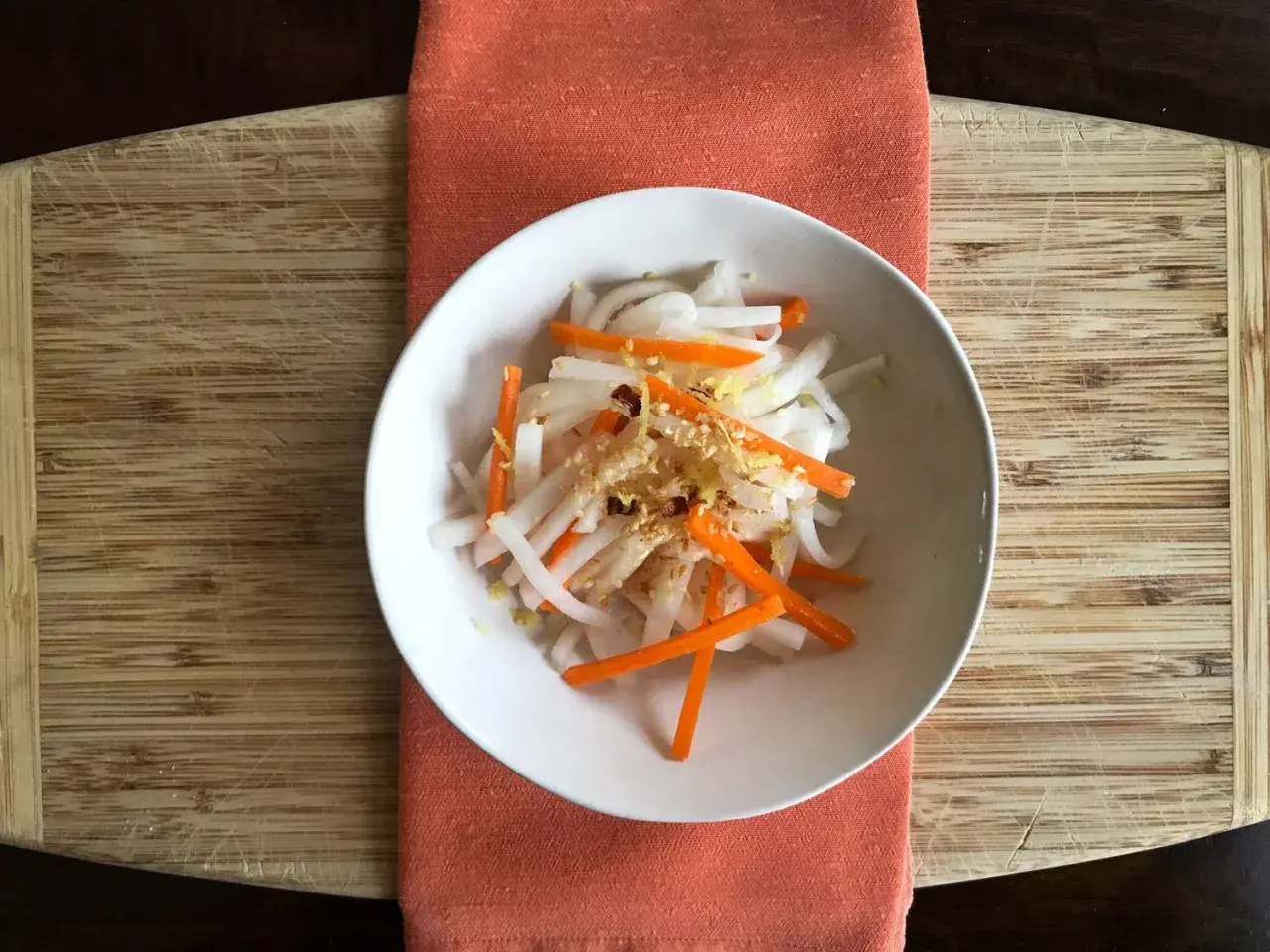 A refreshing namasu recipe with julienned daikon radish and carrots, seasoned with sesame seeds and a hint of citrus zest.