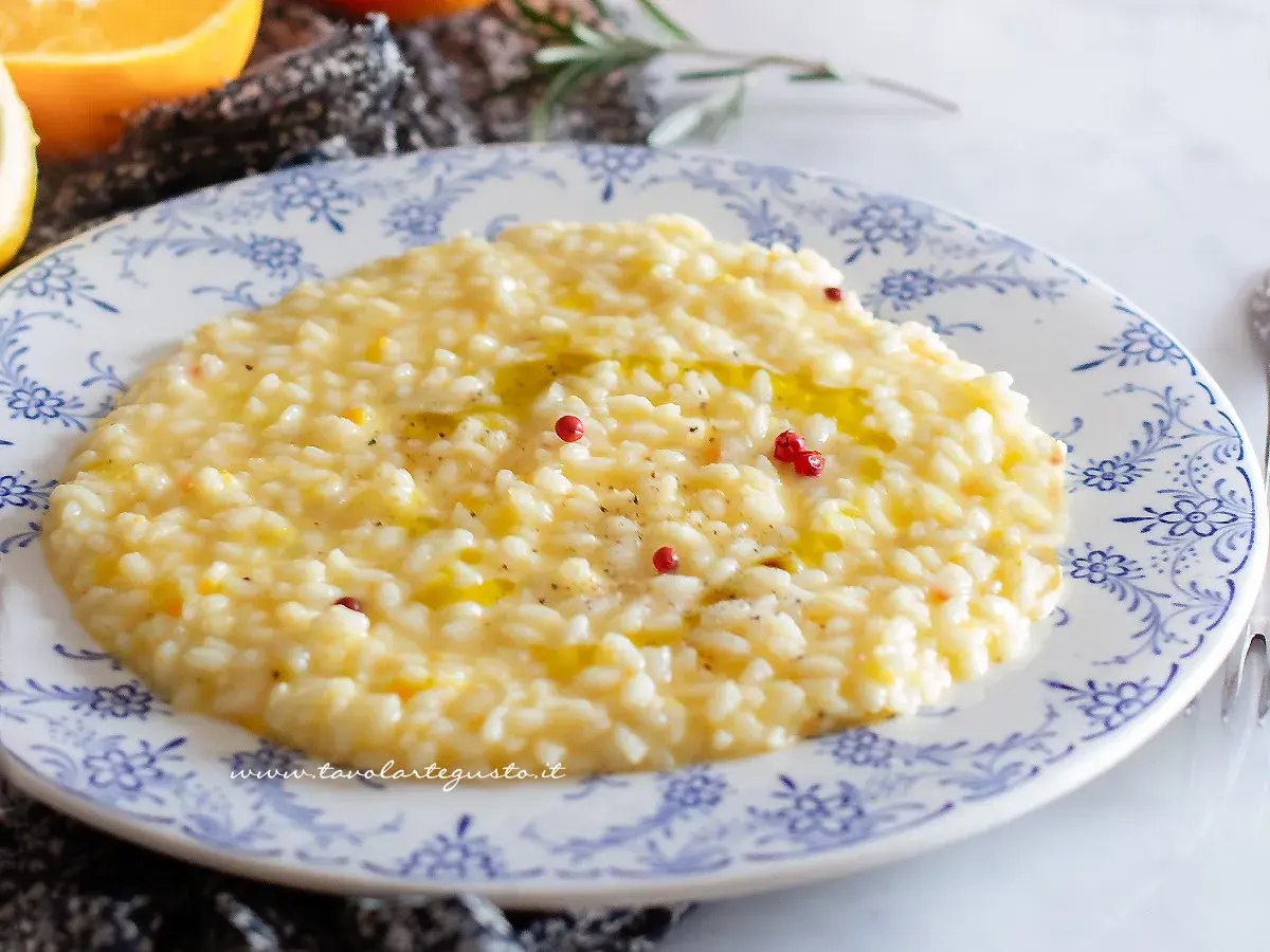 Un cremoso risotto al limone gourmet, guarnito con pepe rosa e un filo d'olio, pronto per essere gustato.