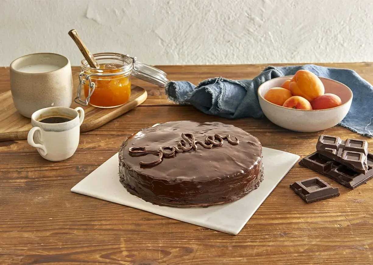 Una deliziosa torta Sacher lucida, con caffè, latte, marmellata di albicocche e cioccolato fondente.