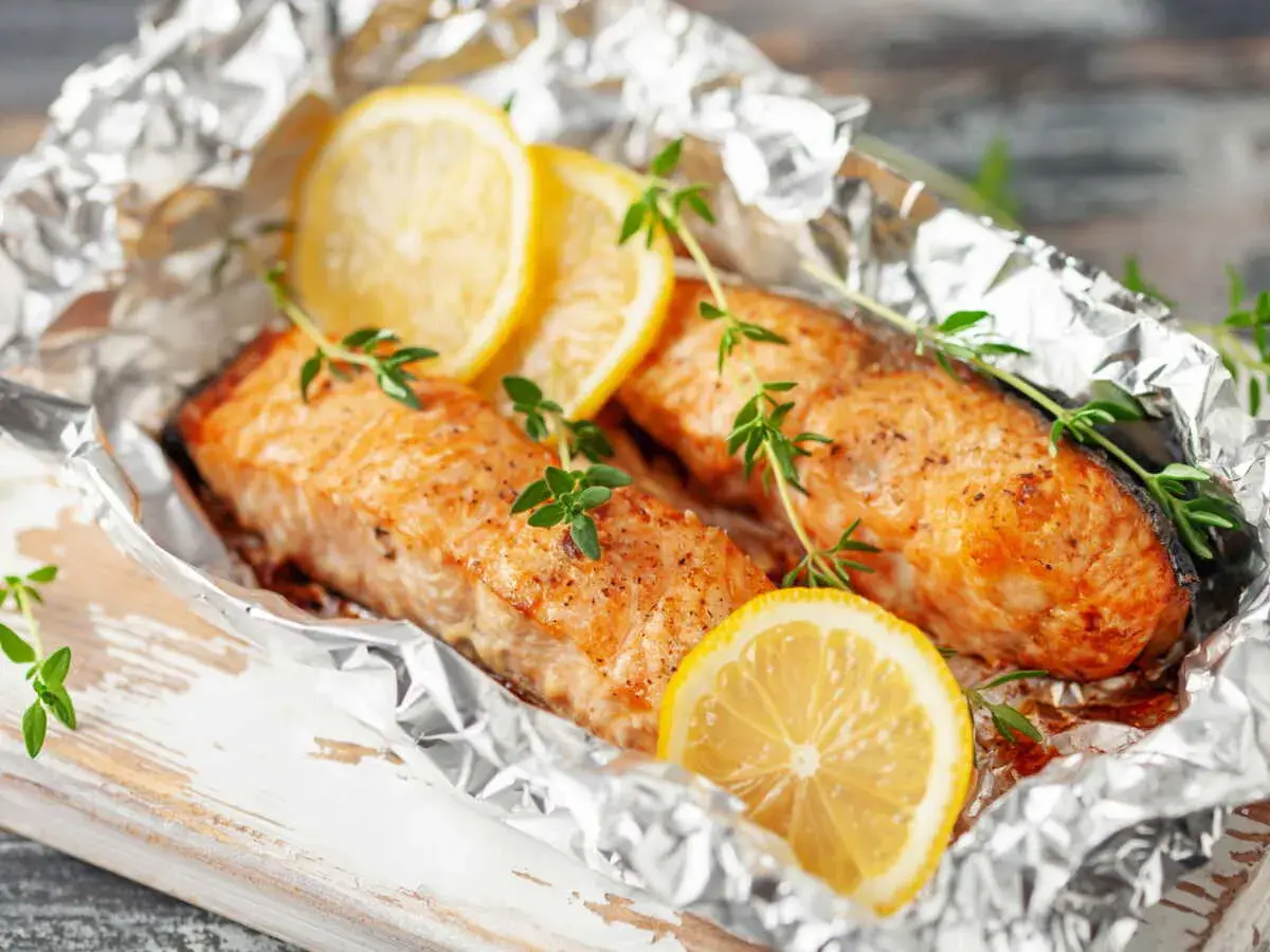 Deux pavés de saumon en papillote, ornés de rondelles de citron et de brins de thym frais, prêts à être dégustés.
