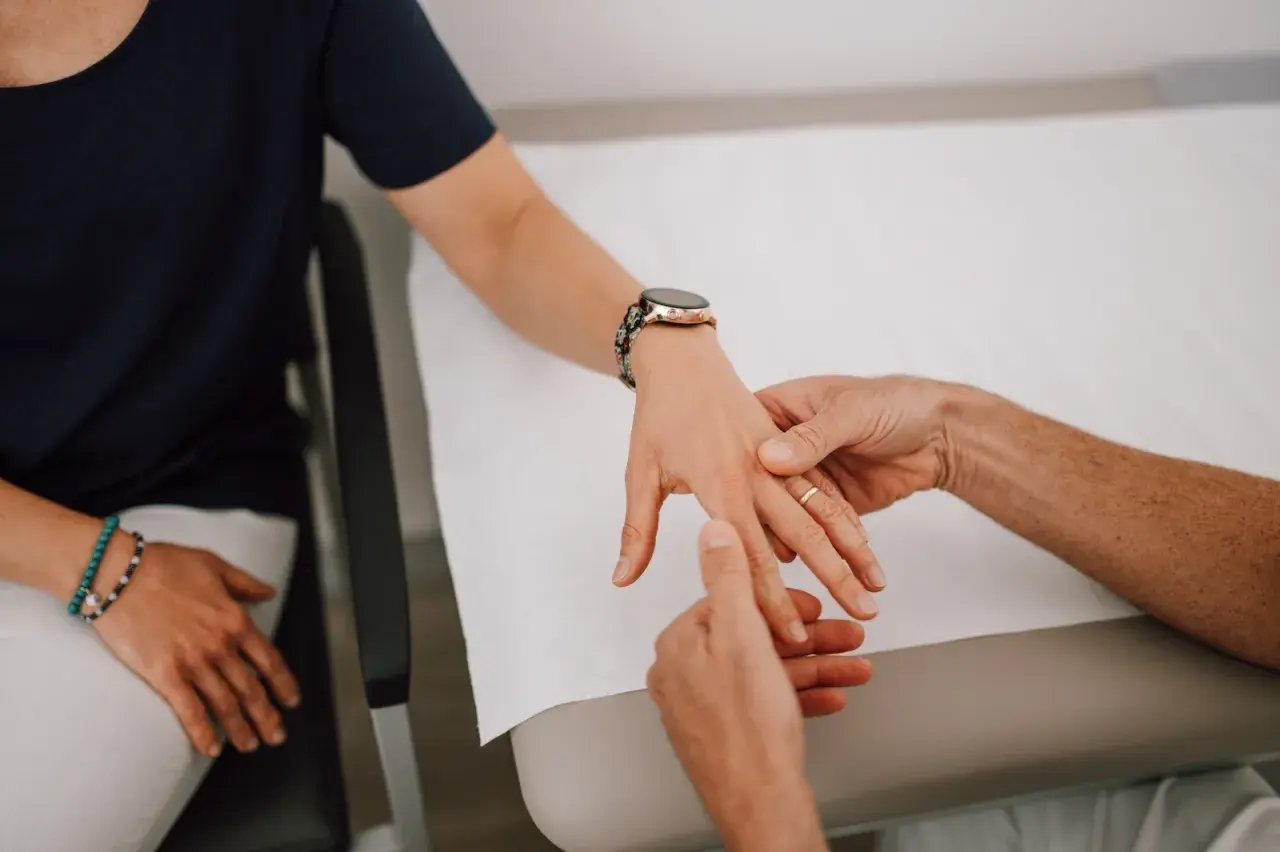 Therapeut untersucht die Hand einer Patientin, um einen Schnappfinger zu behandeln.