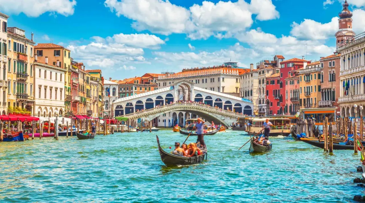 Gondole płynące po Canale Grande w Wenecji, z widokiem na Most Rialto i kolorowe kamienice. Ten region to kwintesencja włoskiego piękna.