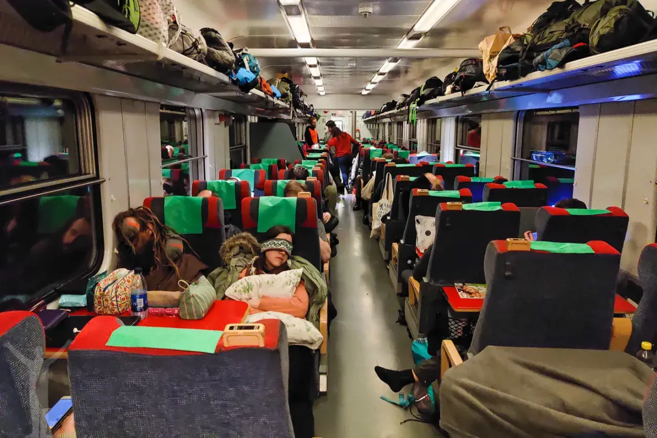 Resenärer sover i en sj sovvagn 2 klass. Bagage ligger på hyllorna ovanför sätena.