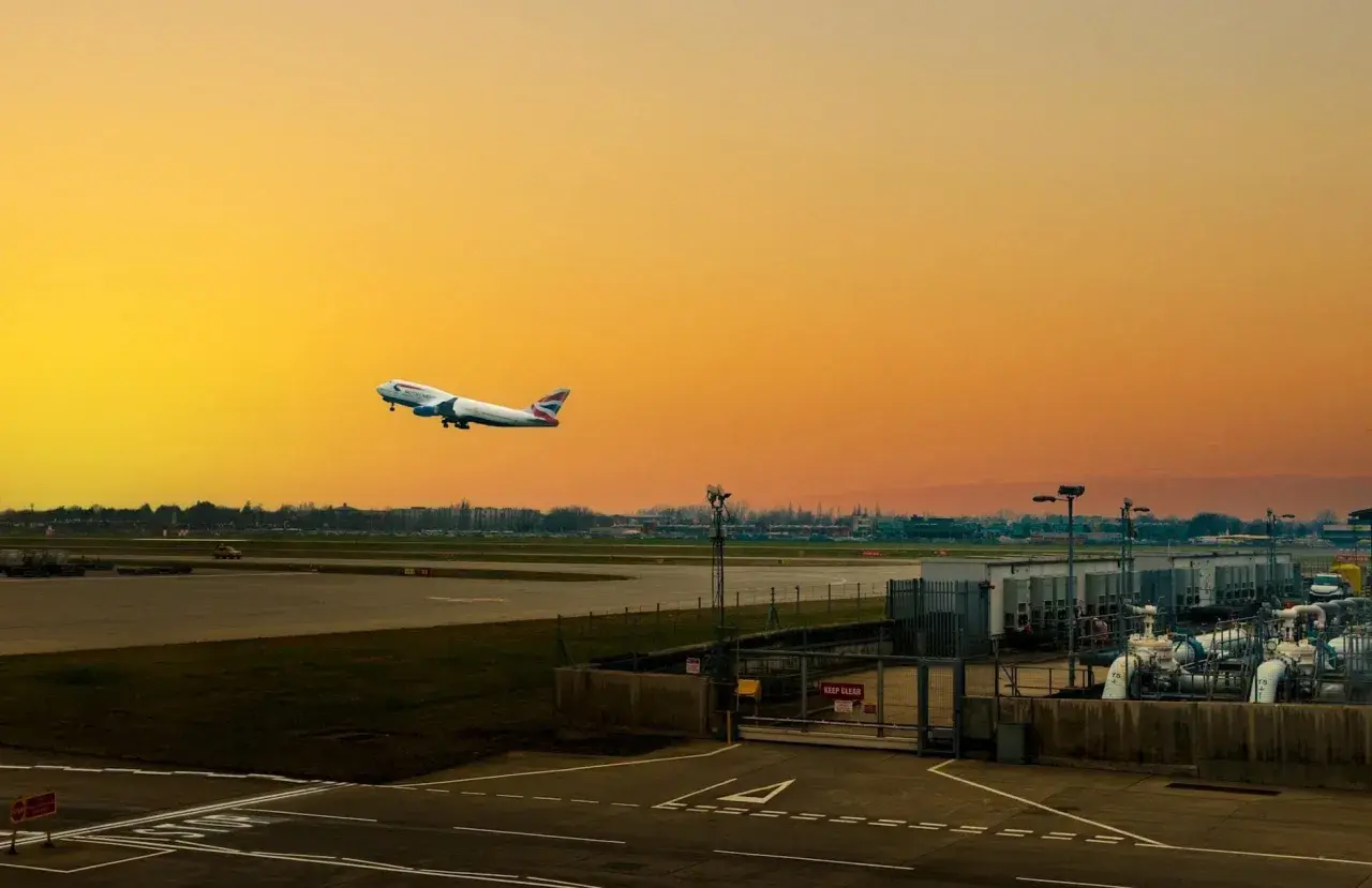 Flugzeug steigt auf vor orangefarbenem Himmel am internationalen Flughafen von London.