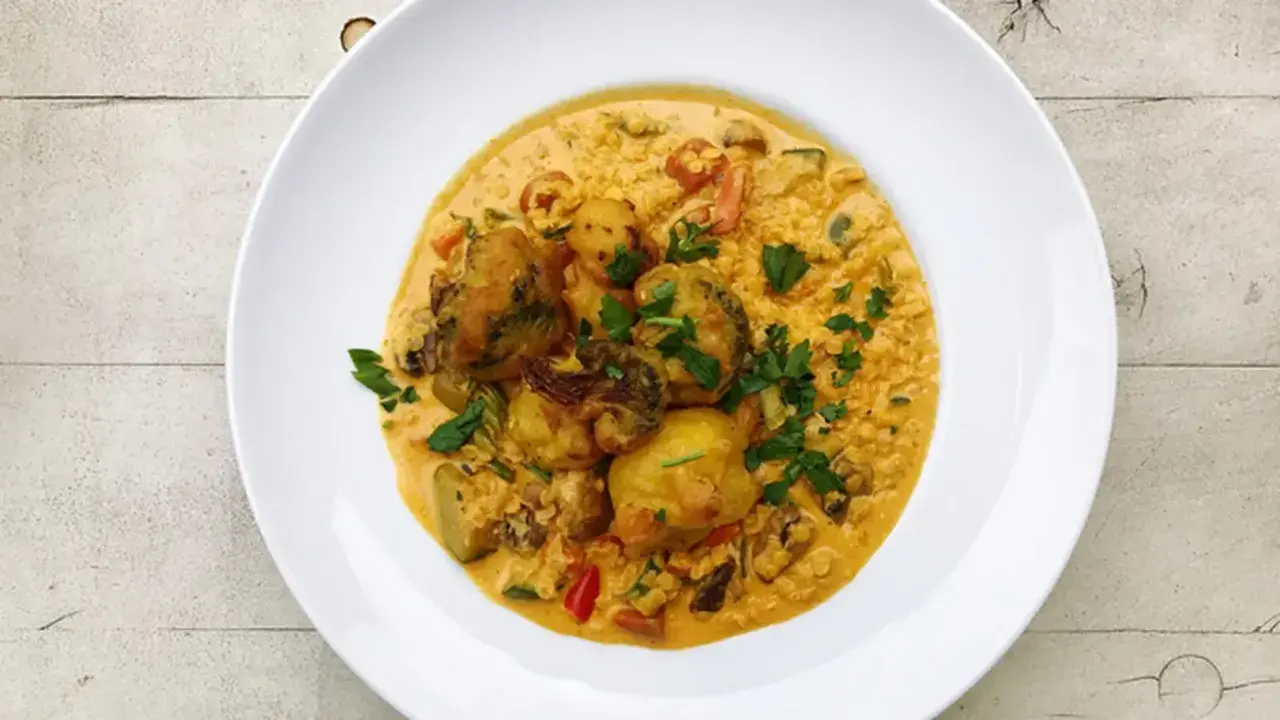 Pyszny ryż z curry z warzywami i kawałkami kurczaka, posypany świeżą natką pietruszki.