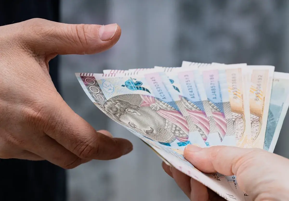 Dwie dłonie przekazują sobie plik banknotów. Zastanawiasz się, ile bank zabiera po śmierci?