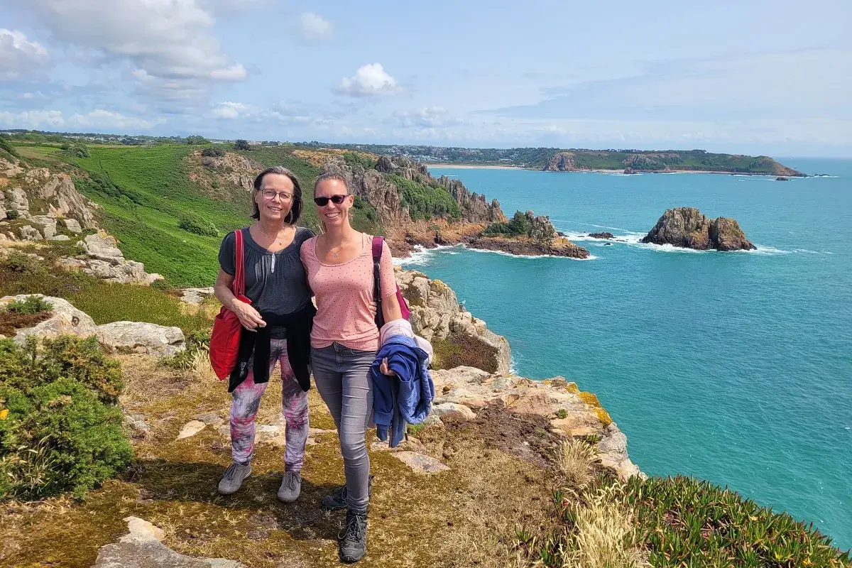 Zwei Frauen genießen den Ausblick auf die Kanalinseln. Tolle kanalinseln urlaub erfahrungen mit türkisfarbenem Meer und Felsen.