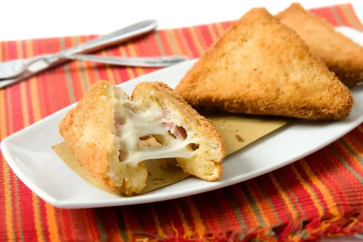 Mozzarella in carrozza in friggitrice ad aria: triangoli dorati e croccanti con cuore filante di mozzarella e prosciutto.