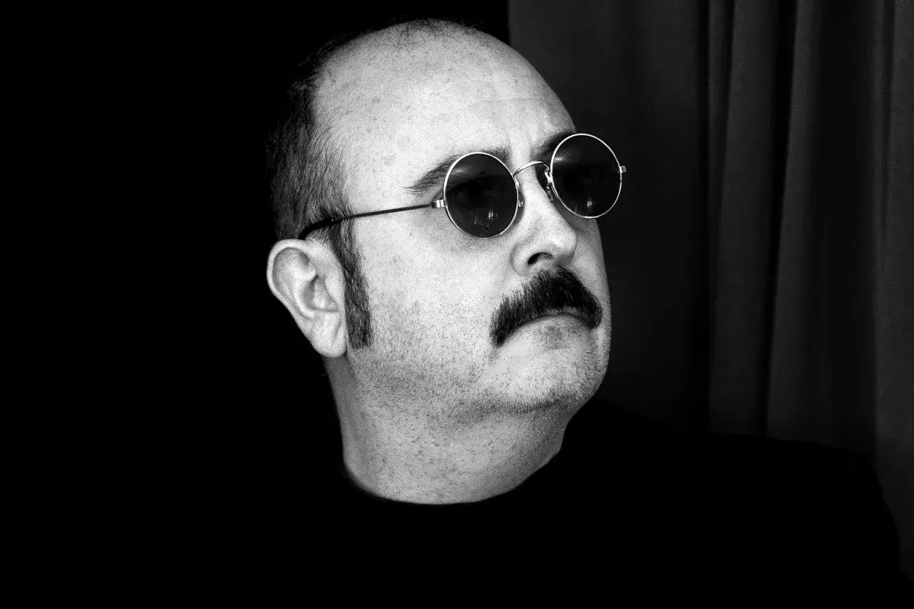 Carlos Areces, con su pareja de gafas redondas y bigote, posa con misterio.