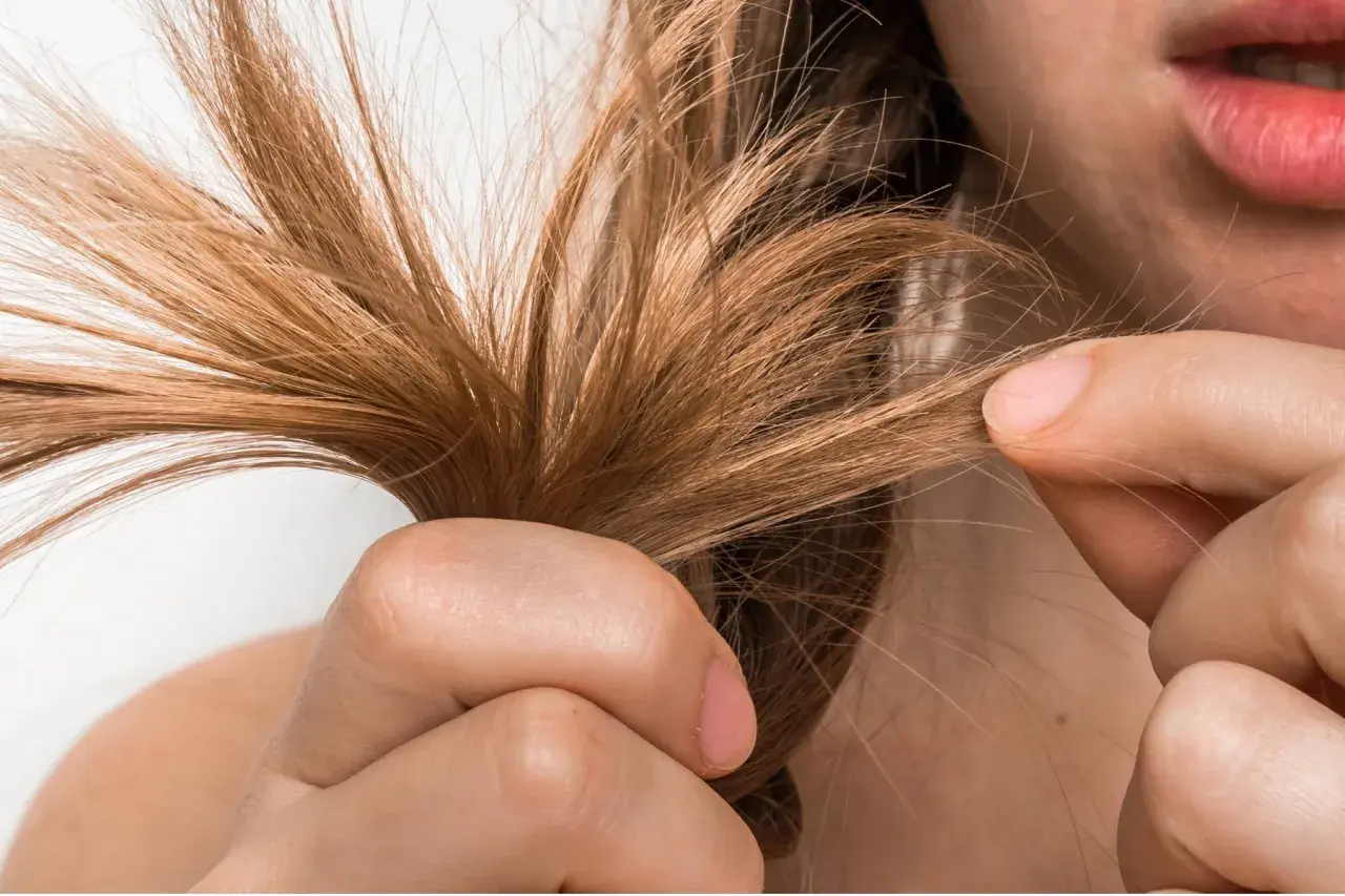 Mujer examinando su cabello fino, buscando soluciones para aumentar densidad capilar mujer.