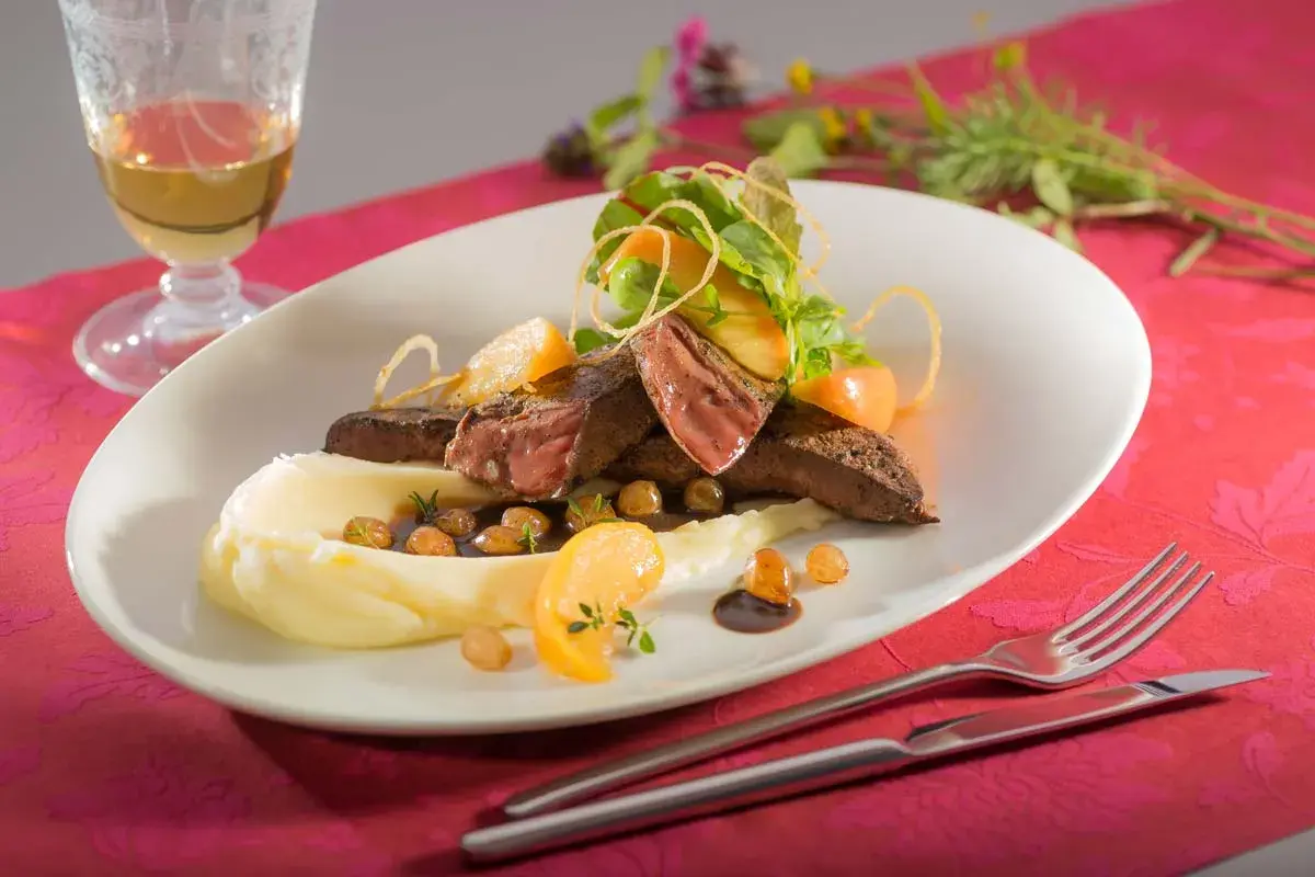 Ein köstliches Kalbsleber Rezept mit Sauce, serviert mit Kartoffelpüree, Apfelspalten und frischen Kräutern.