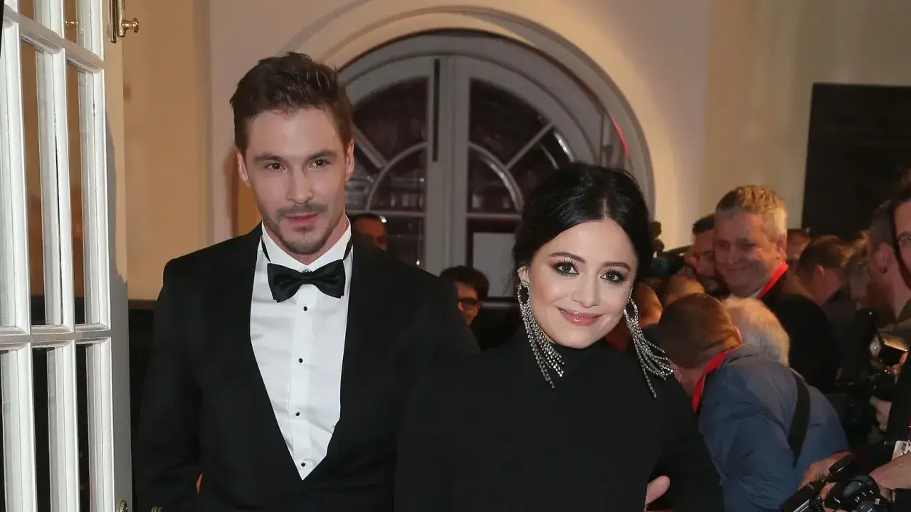 Adriana Kalska z partnerem na czerwonym dywanie, uśmiechnięci i eleganccy.