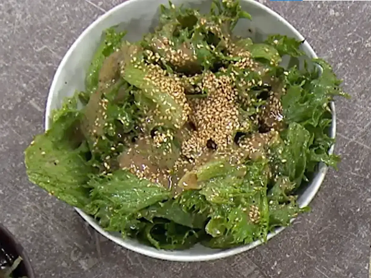 Grön, krispig sallad med sesamfrön och en dressing, perfekt som sallad till paj.