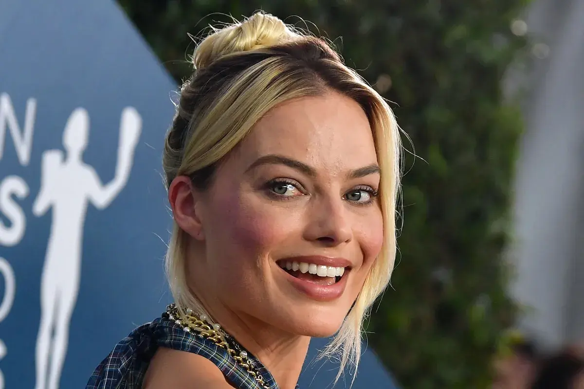 Margot Robbie, l'actrice qui incarne Harley Quinn, rayonne avec un chignon blond et un sourire éclatant.