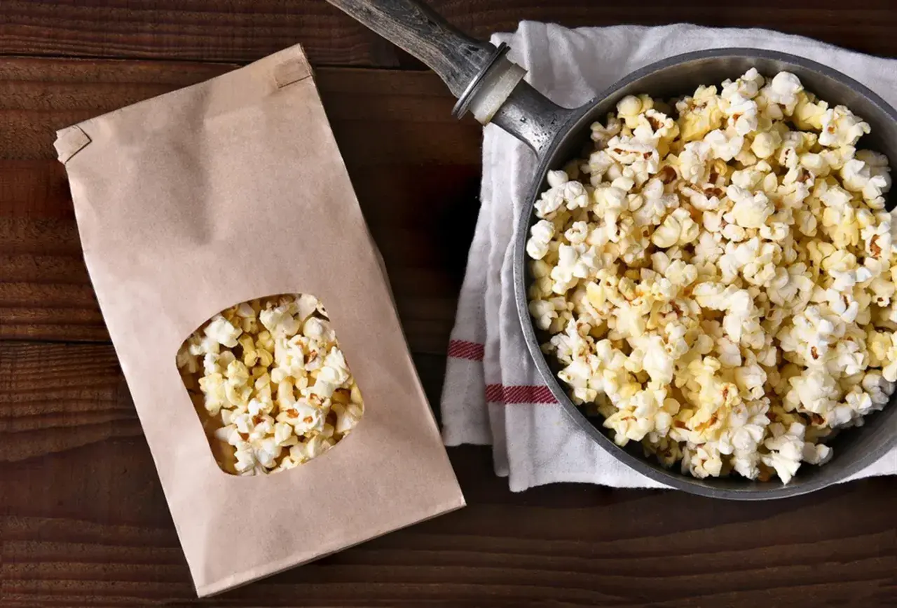Jak zrobić popcorn w garnku? Świeżo przygotowany popcorn w garnku i papierowej torbie, gotowy do chrupania.