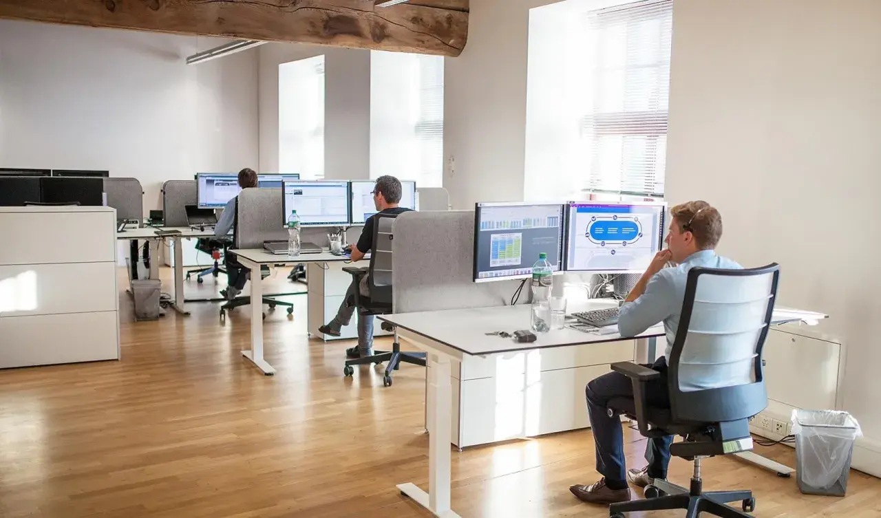 Bureau moderne avec employés travaillant sur des ordinateurs. Un homme utilise un service de bureau cloud pour gérer des données.