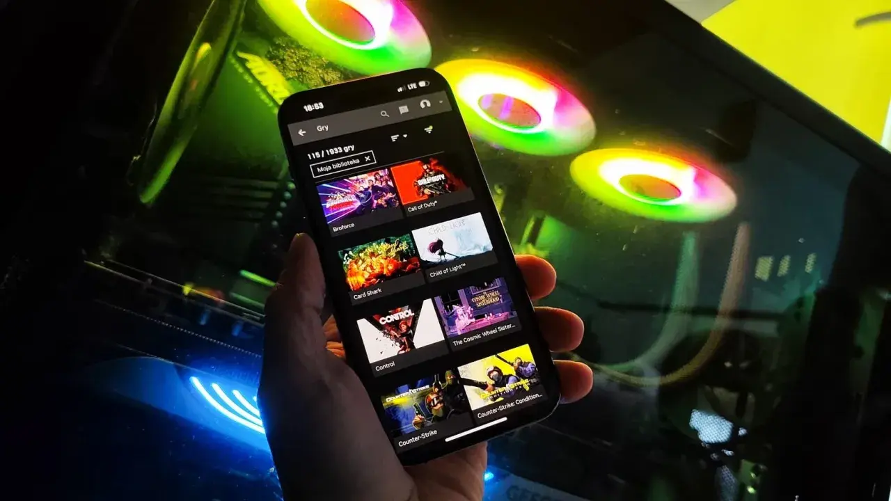 Przeglądanie listy gier na GeForce Now na telefonie, w tle świecące wentylatory komputera.