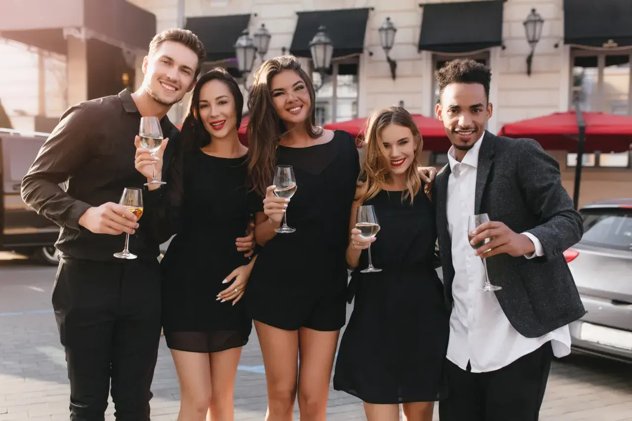 Fünf Freunde in eleganter Cocktailgarderobe stoßen mit Champagner an.