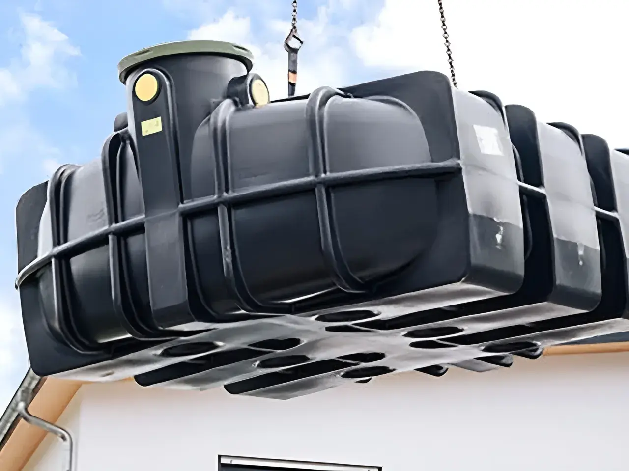 Schwarzer Tank wird mit Kran gehoben, bereit zum zisterne einbauen.