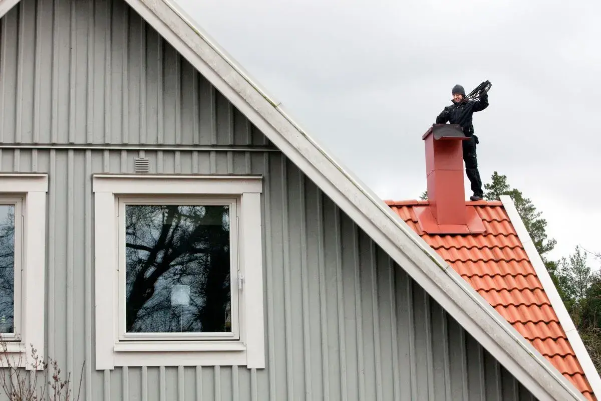 Sotare på taket till en villa. Regelbunden sotning är viktigt för säkerheten.