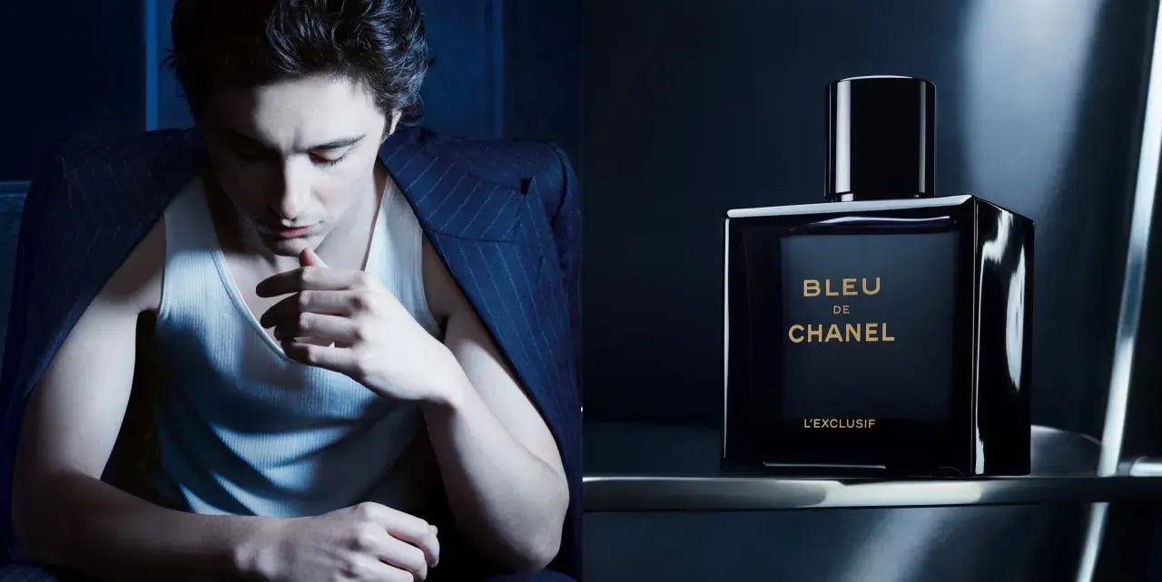 Młody mężczyzna w garniturze i podkoszulku, obok flakonik perfum BLEU DE CHANEL L'EXCLUSIF.