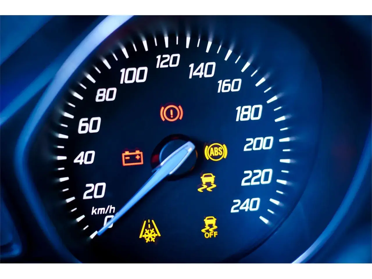 Cruscotto auto con tachimetro e spie accese: spia punto esclamativo giallo, ABS, controllo stabilità e batteria.