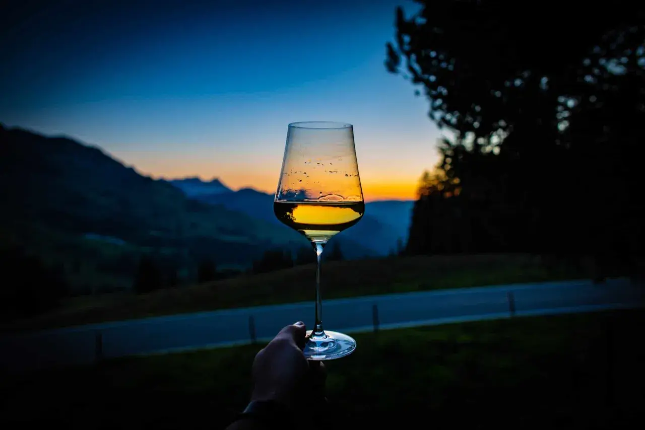 Un calice di vini aromatici riflette il tramonto sulle montagne.