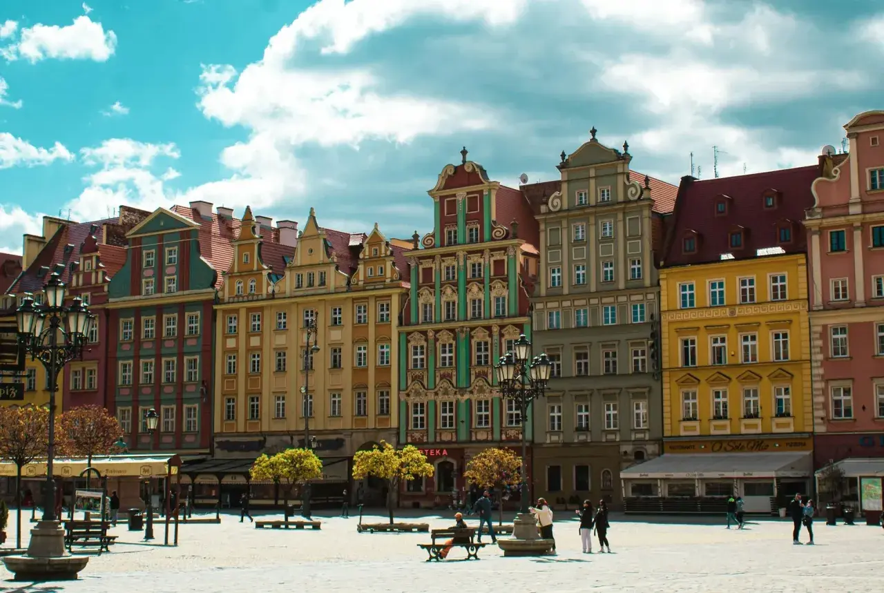 Kolorowe kamienice na wrocławskim Rynku, idealne na city break z Wrocławia. Słoneczny dzień, chmury na niebie.