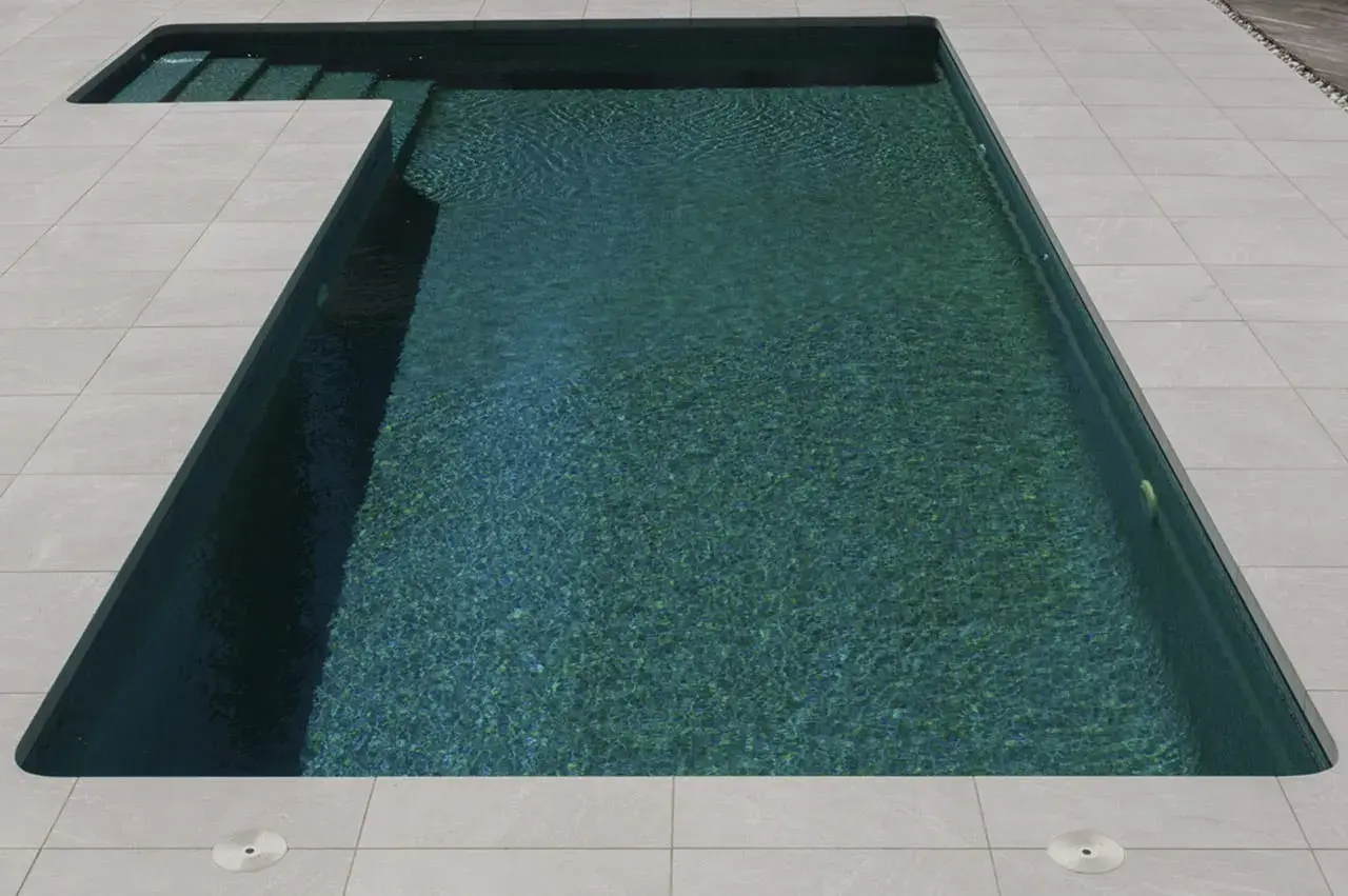 Bordes de piscinas modernas con escalones integrados y un revestimiento de baldosas claras que contrastan con el agua turquesa.