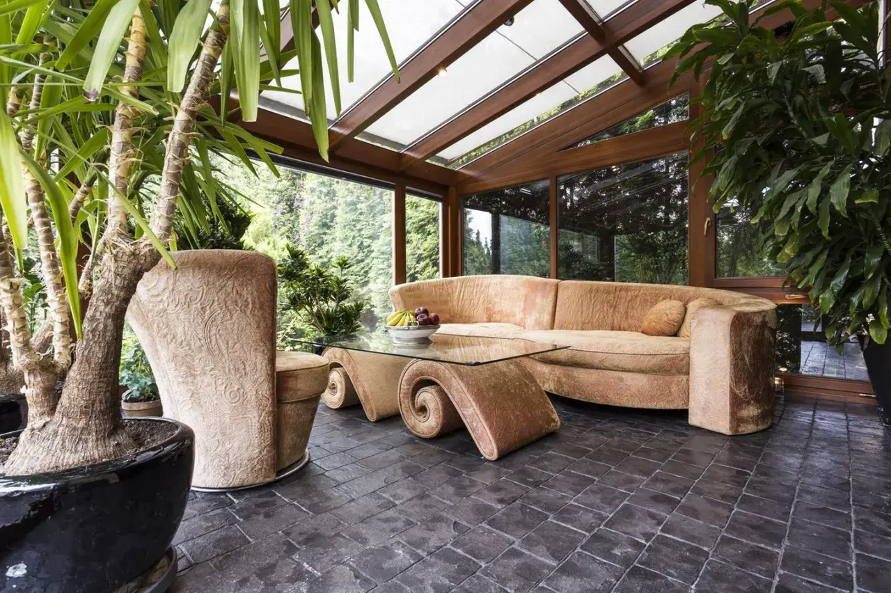 Gemütlicher Wintergarten mit üppiger Bepflanzung, bequemer Couch und einem einzigartigen Couchtisch. Tolle Ideen für Ihren Wintergarten!