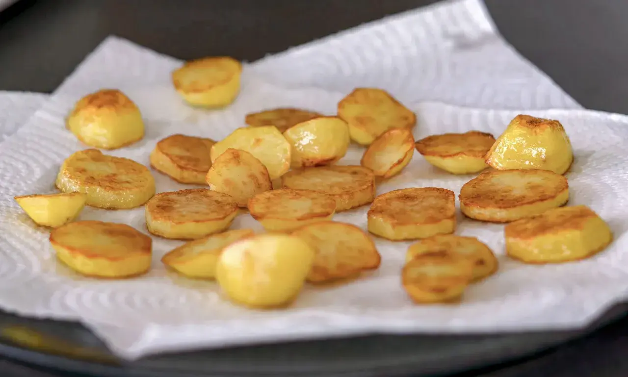 Patatas al horno recién hechas, doradas y crujientes, reposando sobre papel absorbente. ¡Listas para disfrutar!