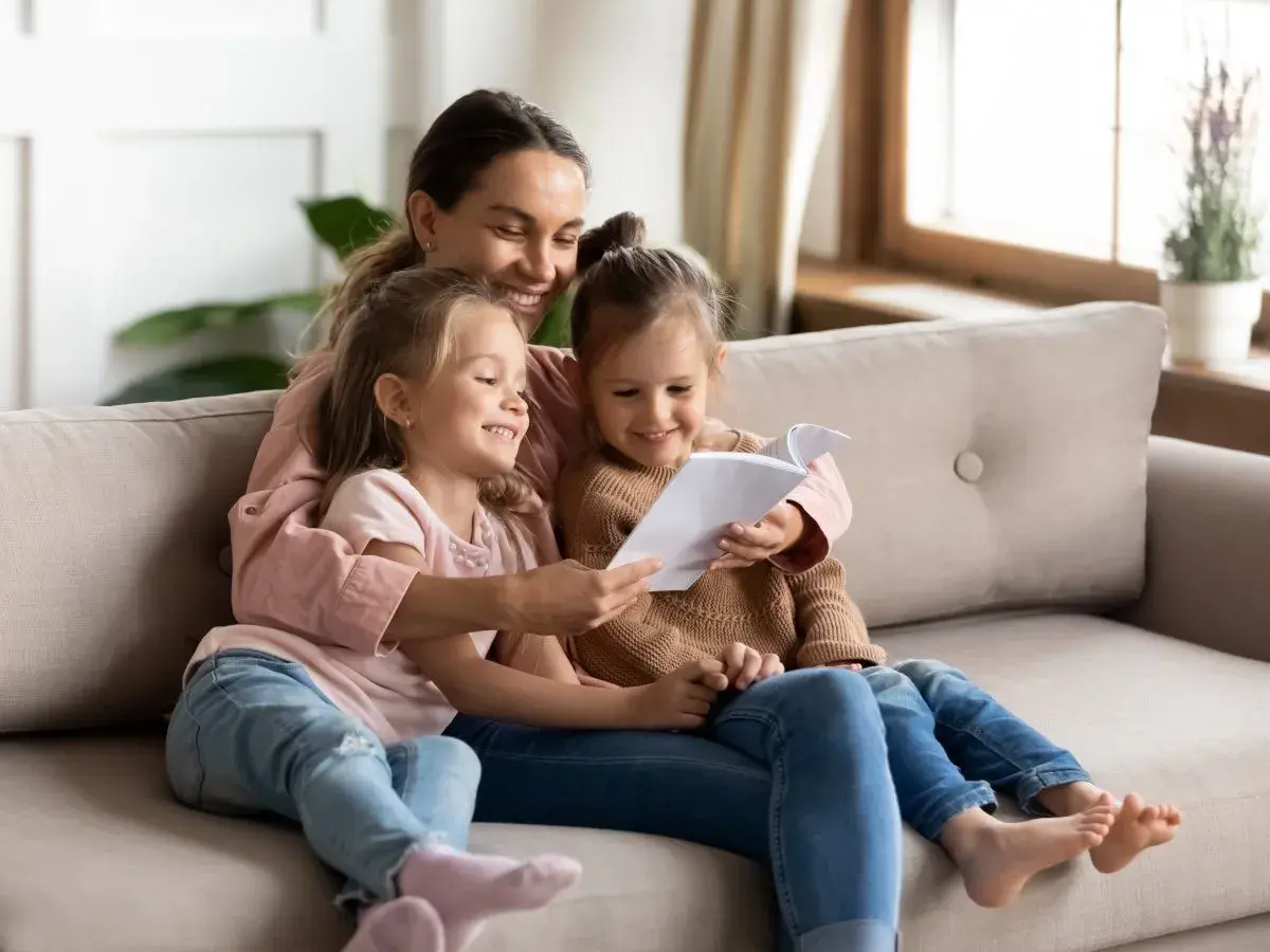 Mama czyta swoim córeczkom krótkie wierszyki dla bff. Radość i bliskość na kanapie.