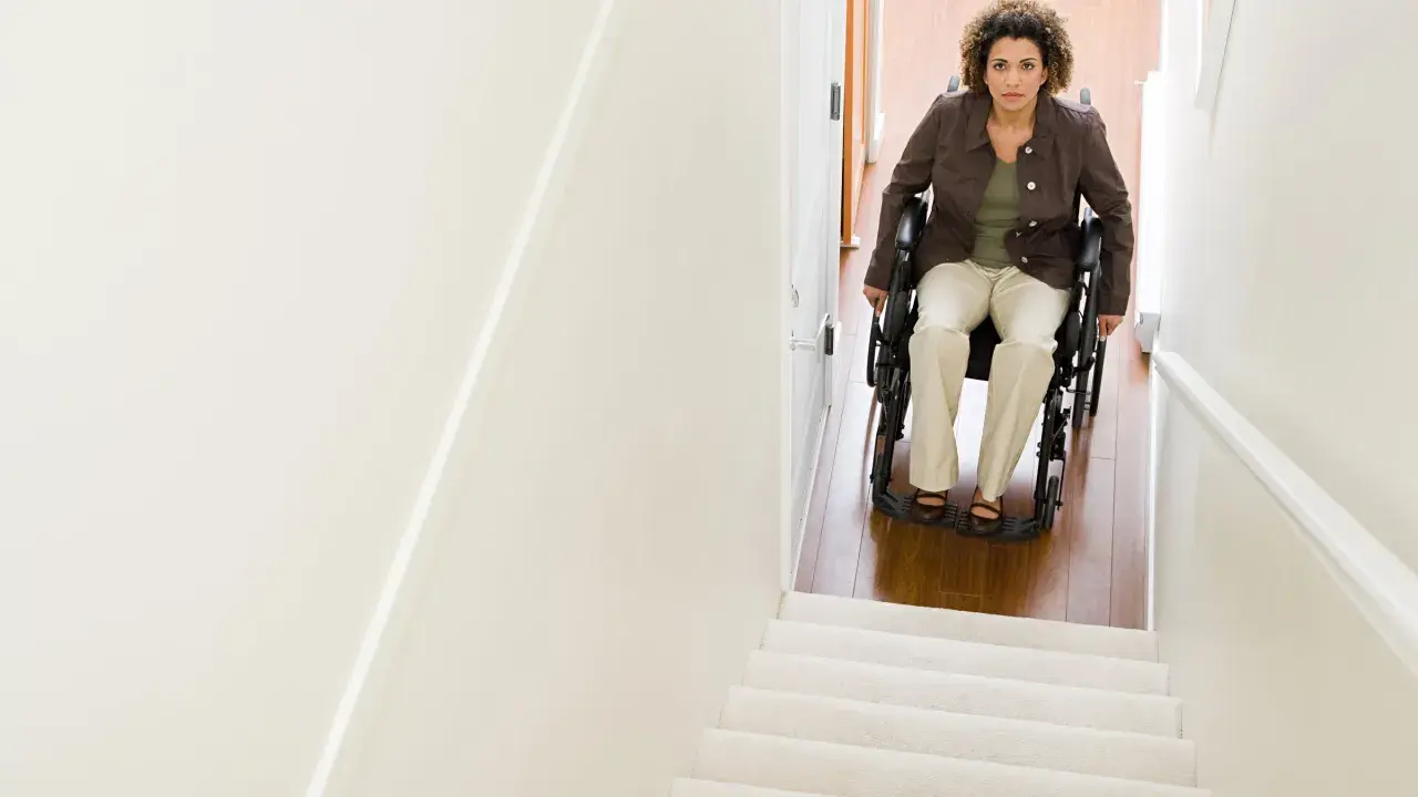 Donna in carrozzina guarda verso l'alto, pronta per il trasporto disabile su per le scale.