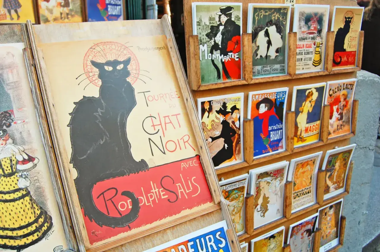 Affiches de chat art, dont une grande affiche du Chat Noir, exposées sur un présentoir en bois.