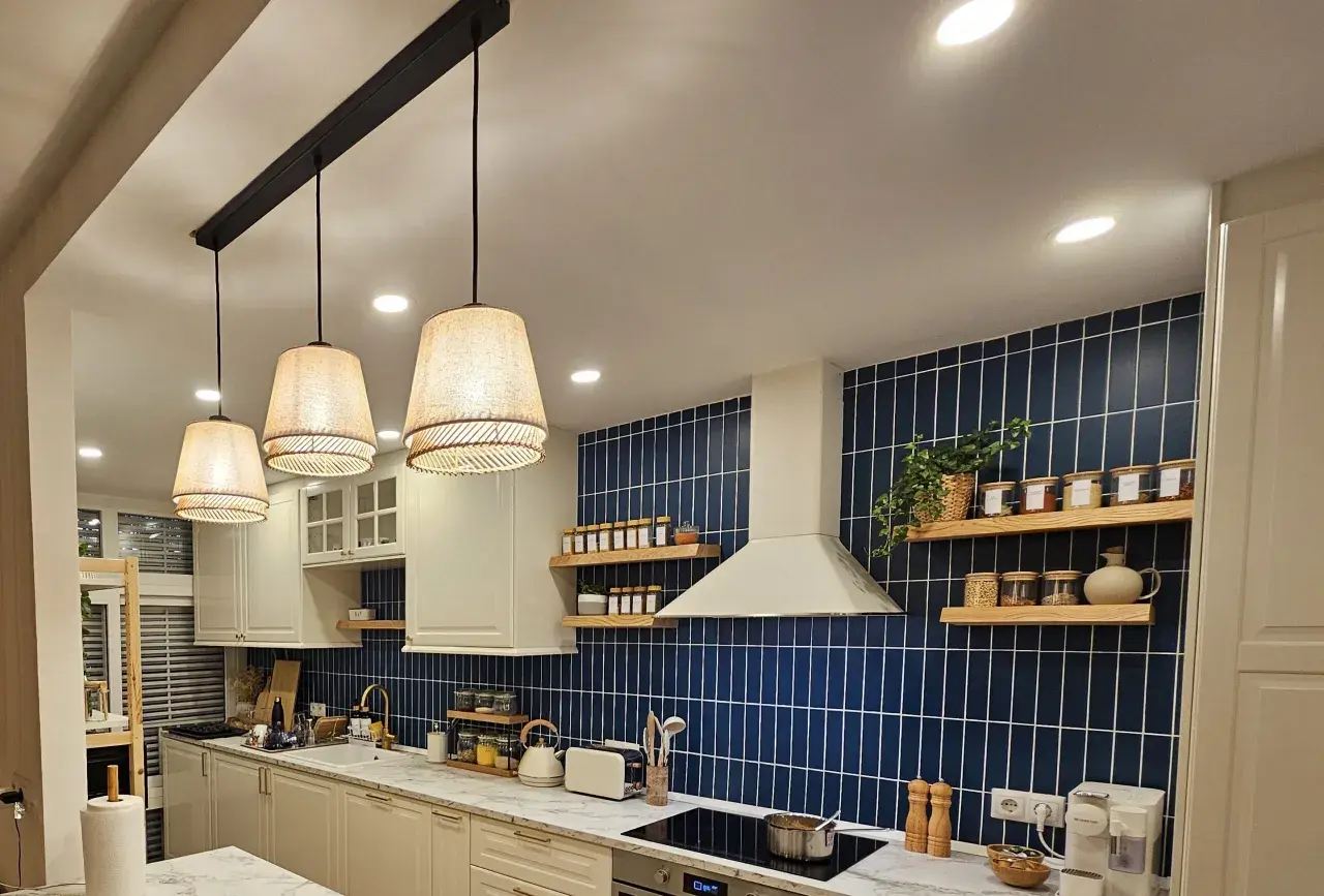 Una lámpara negra y madera ilumina esta cocina moderna con azulejos azules y encimeras de mármol.