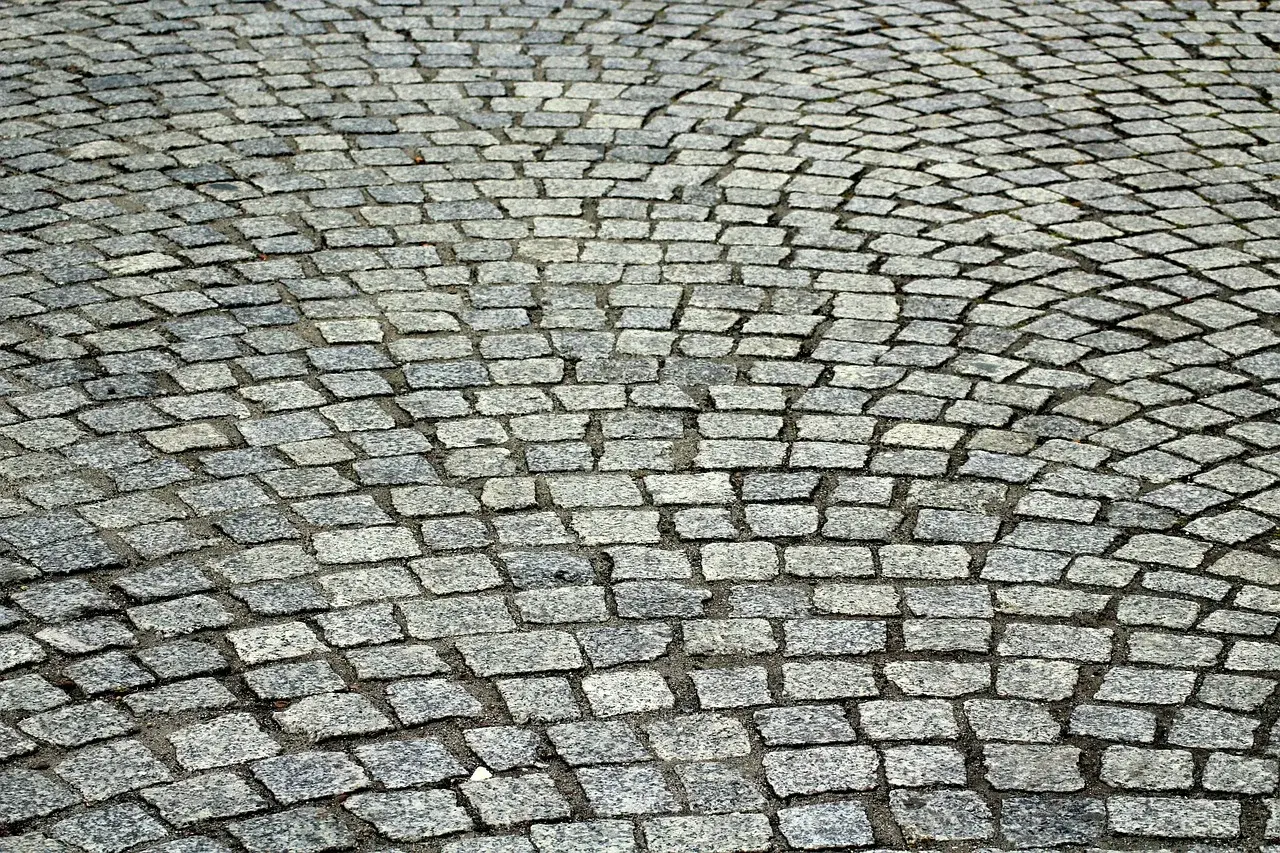Szara kostka granitowa ułożona łukiem. Dokładne ile kostki granitowej na m2 zależy od jej wymiarów.