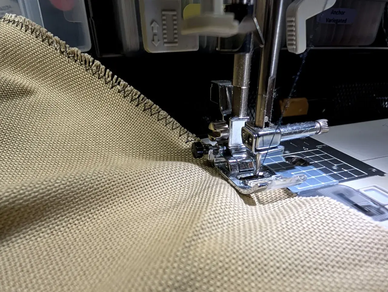 Sewing a zigzag stitch on a tan fabric to prevent fraying. This technique helps keep edges neat, unlike how some flannel might fray.