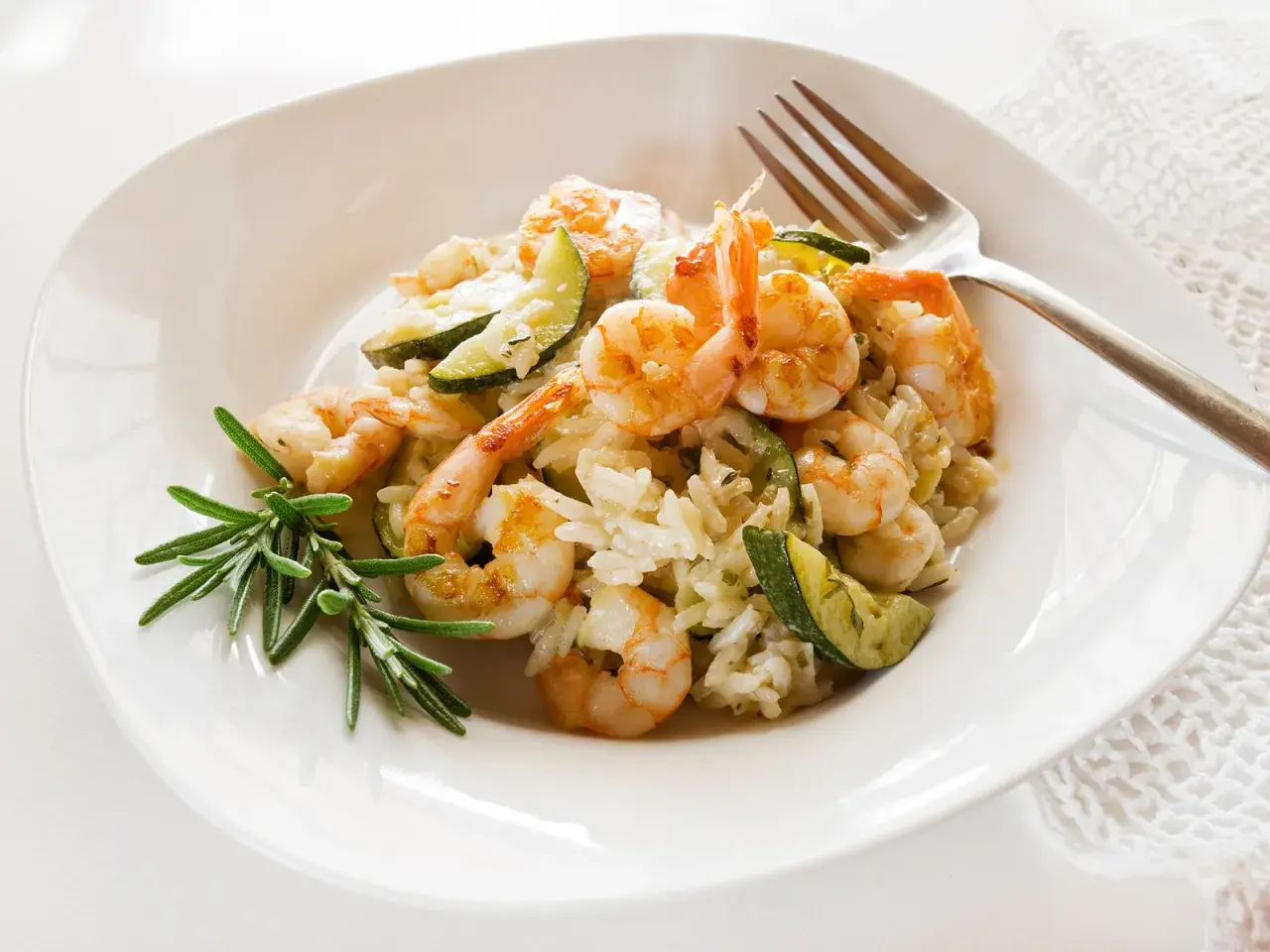 Cremiges Risotto mit Garnelen und Zucchini, garniert mit Rosmarin. Ein köstliches Gericht, das Lust auf mehr macht.