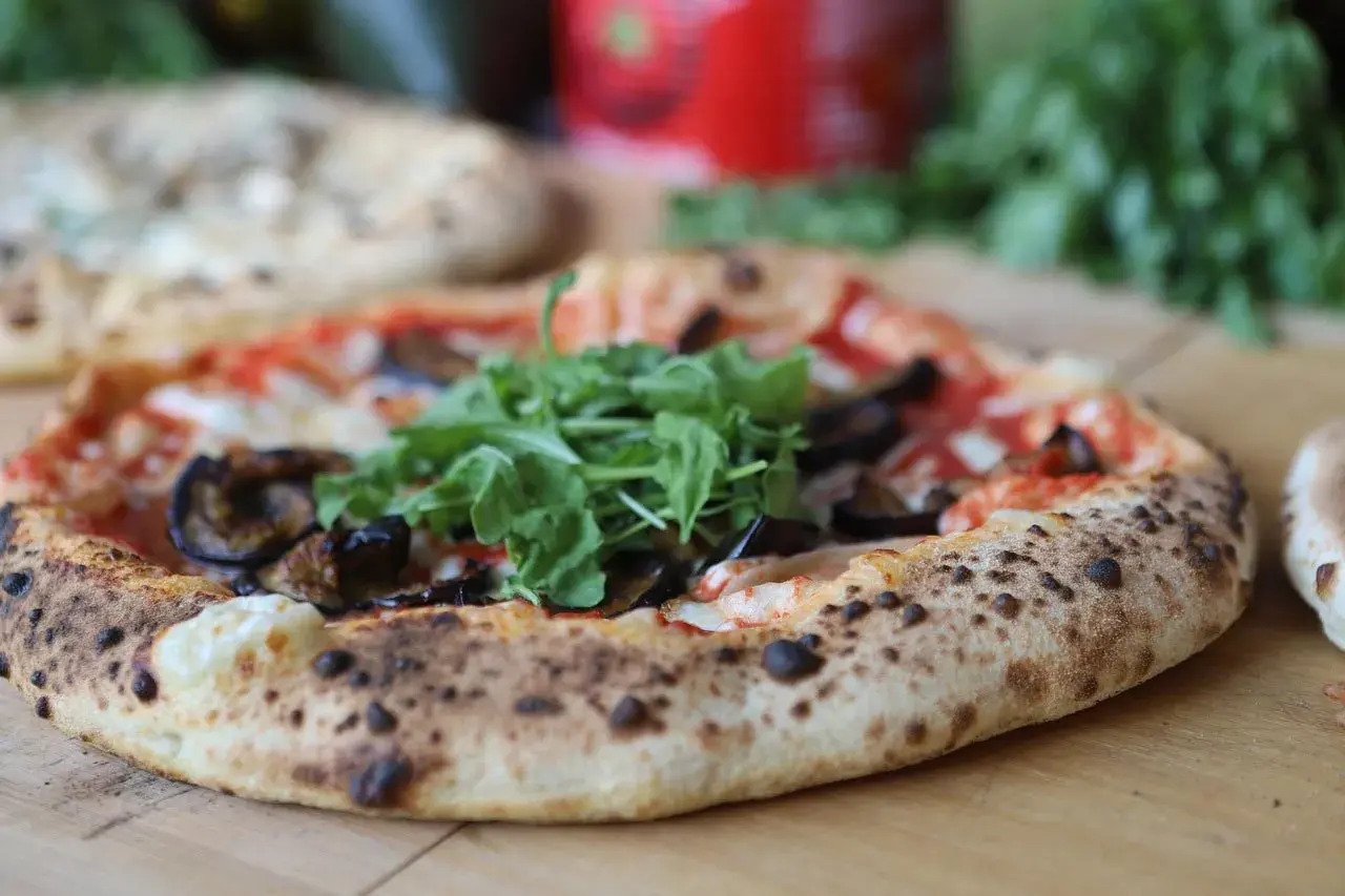 Eine köstliche neapel pizza mit Auberginen und Rucola, frisch aus dem Ofen.